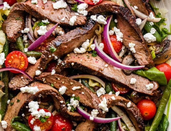 Steak Salad served on a long plate topped with cheese crumbles, tomatoes, and mushrooms