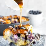A Spouted Measuring Cup Drizzling Maple Syrup Over a Piece of French Toast Casserole