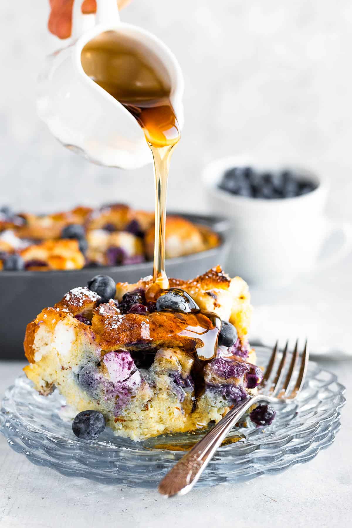 A Spouted Measuring Cup Drizzling Maple Syrup Over a Piece of French Toast Casserole