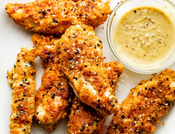 Everything Bagel Chicken Tenders arranged on a round plate and served with honey mustard dipping sauce