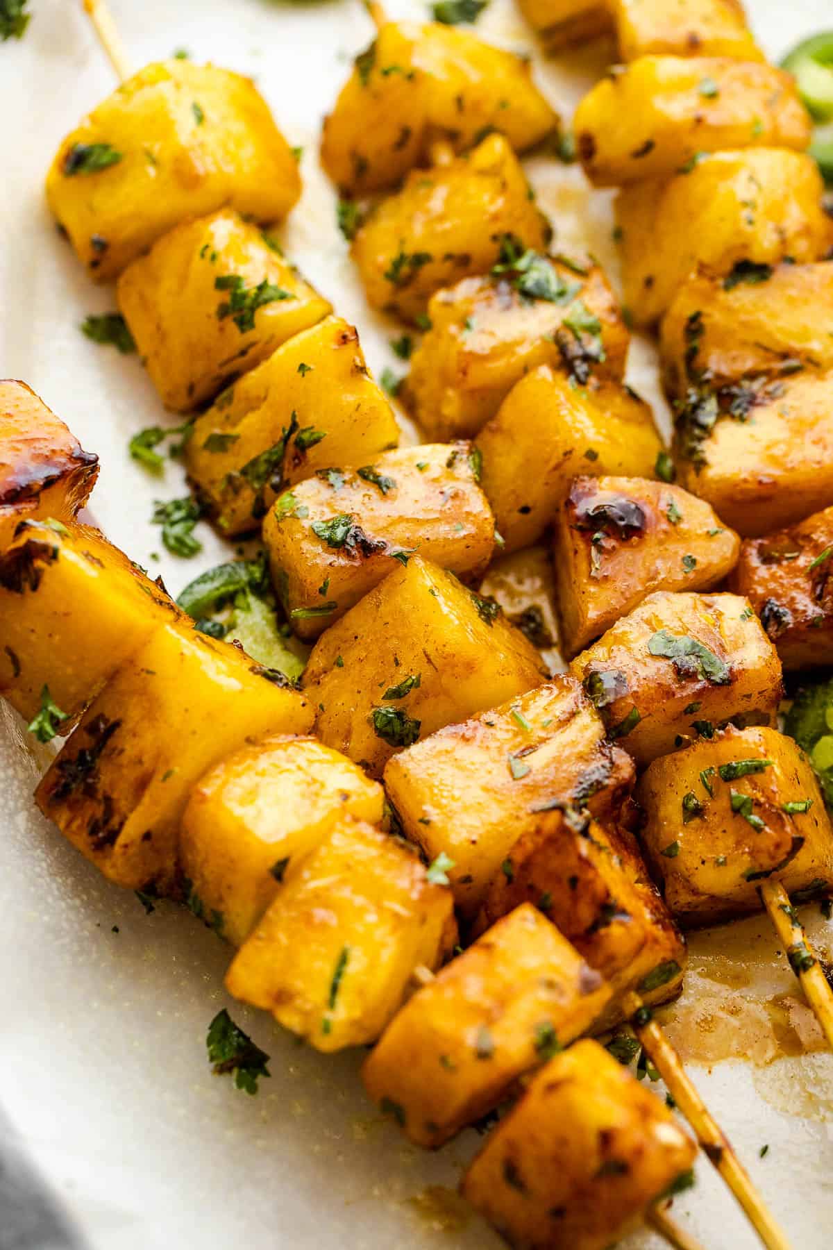 side shot of pineapple skewers topped with chopped cilantro