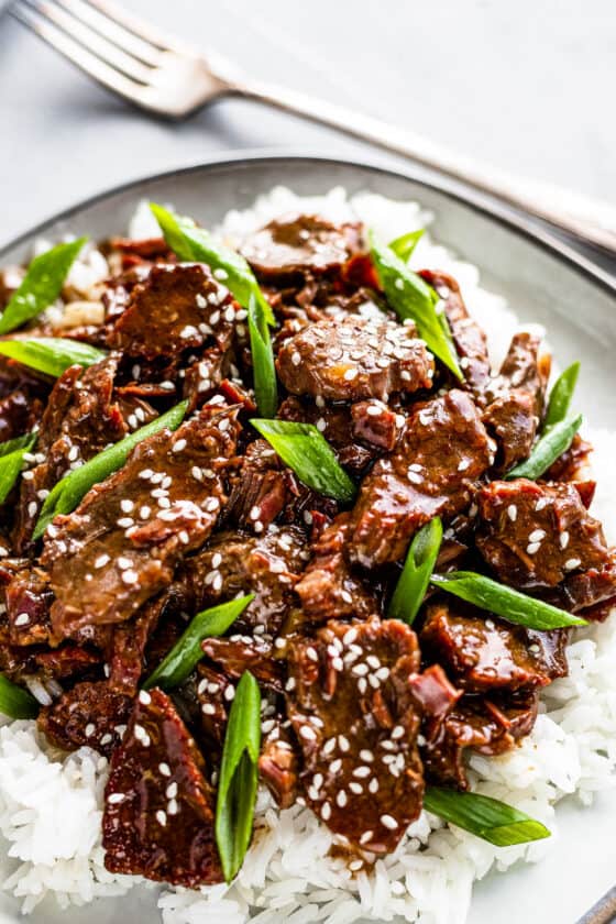 Instant Pot Mongolian Beef Over White Rice on a Gray Plate with a fork on the side