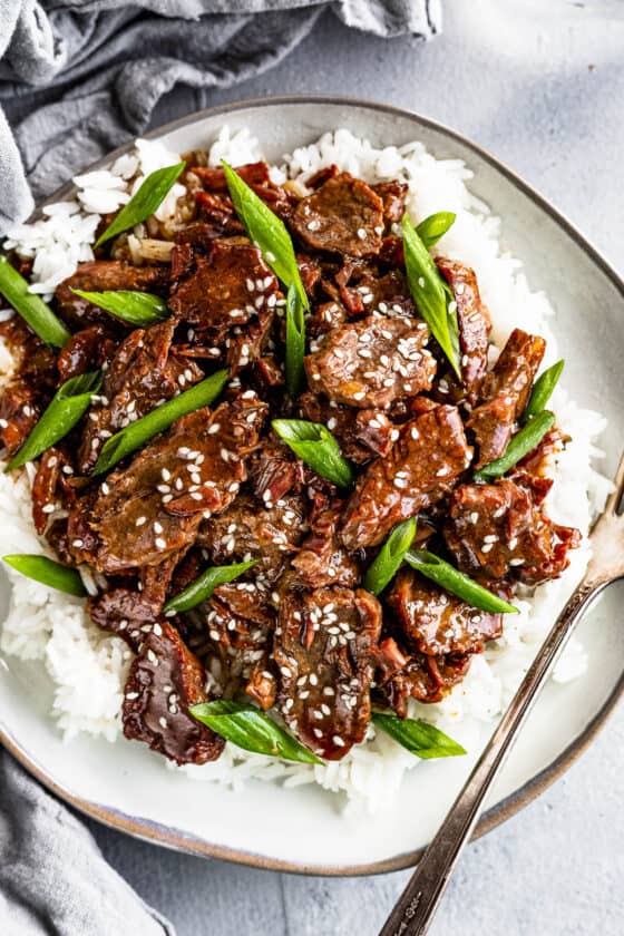 Instant Pot Mongolian Beef Over White Rice on a Gray Plate with a fork on the plate