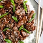 Instant Pot Mongolian Beef Over White Rice on a Gray Plate with a Pair of Wooden Chopsticks