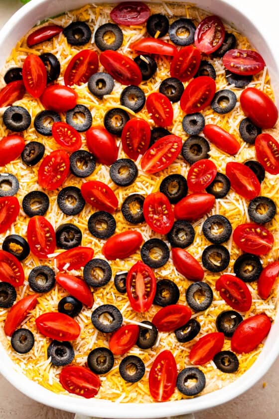 overhead shot of a white baking dish with halved cherry tomatoes and sliced olives