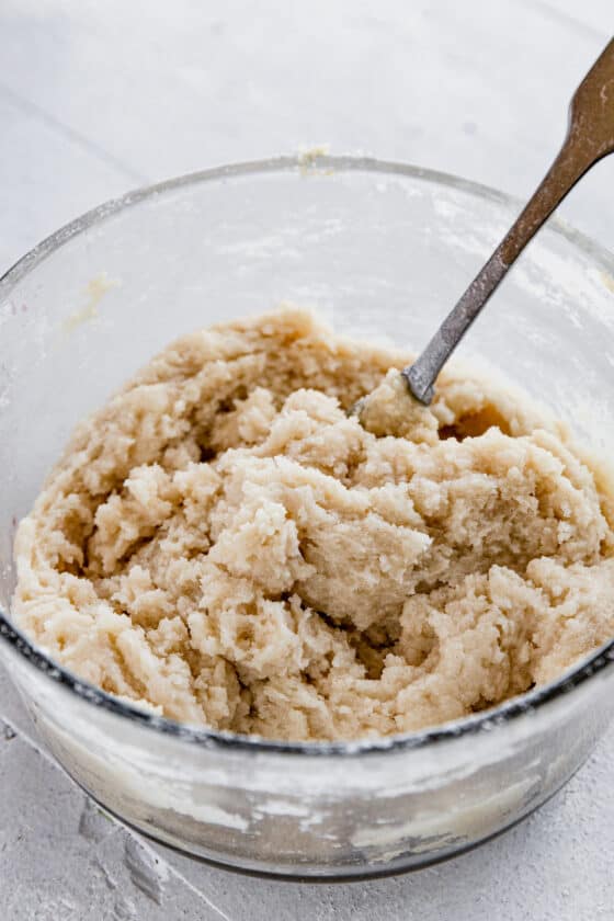 The Dough for the Topping of the Crisp in a Glass Bowl with a Metal Spoon