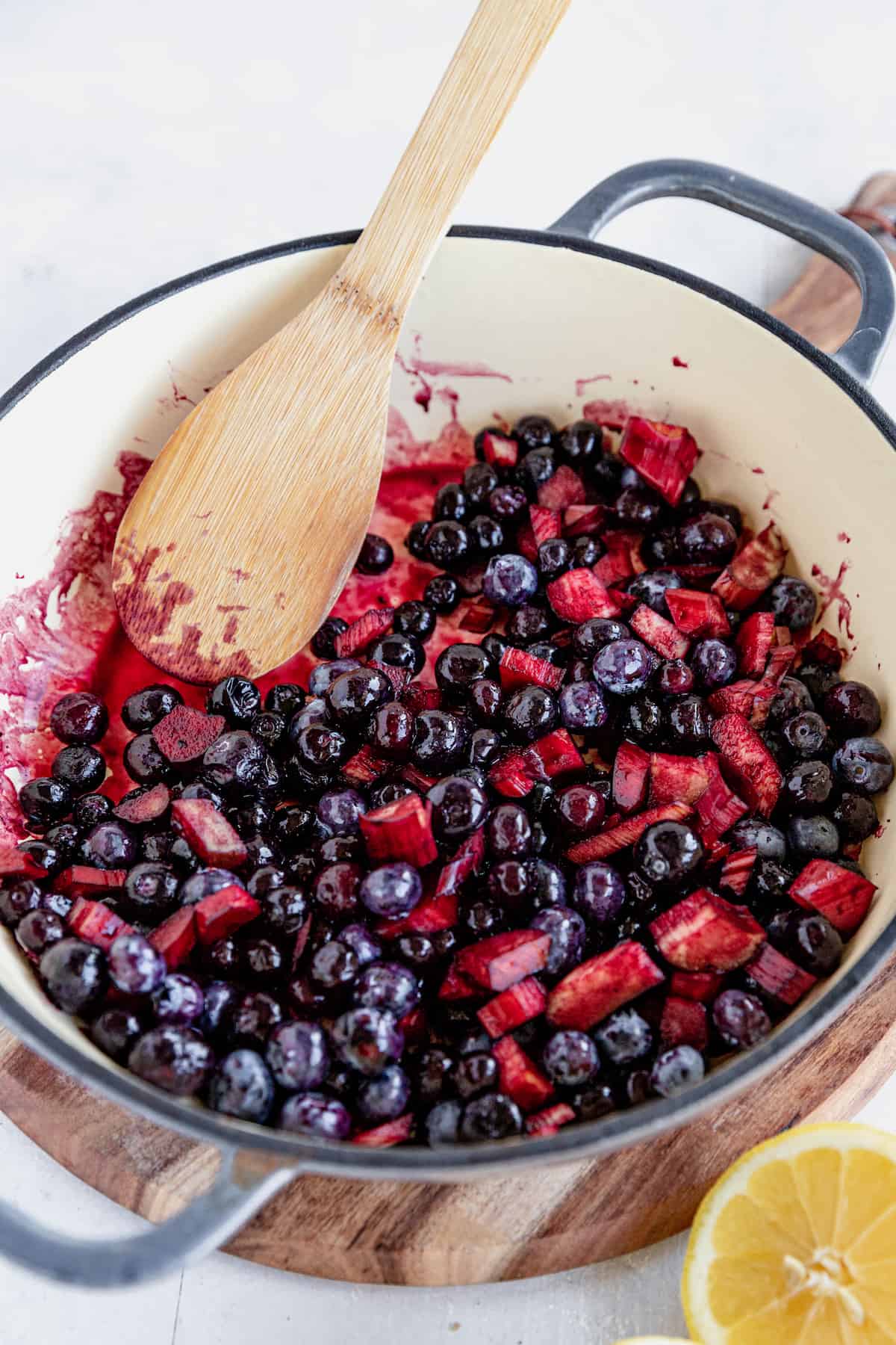 The Filling for Blueberry Rhubarb Cobbler in a Skillet Being Mixed with a Wooden Spoon