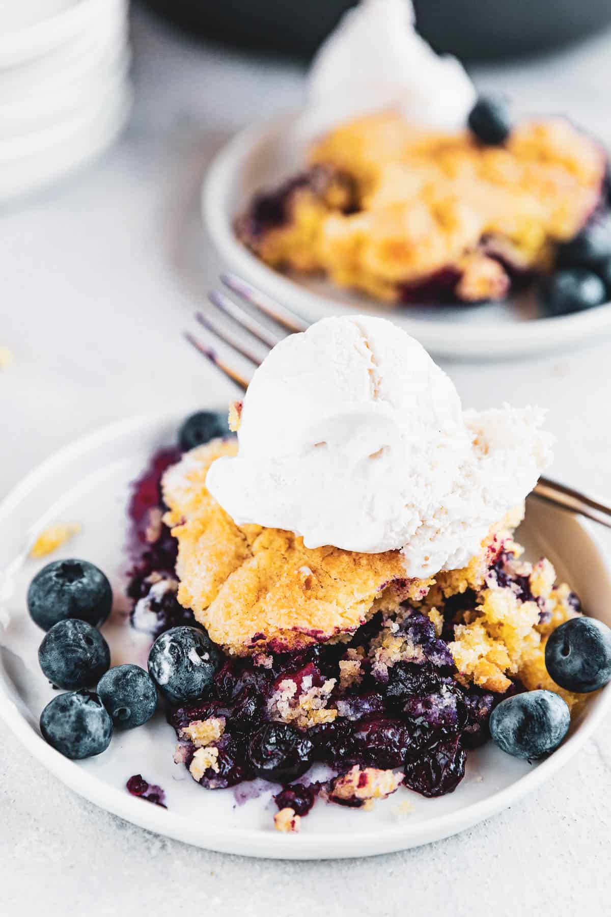Blueberry Rhubarb Cobbler served on a plate and topped with ice cream scoop