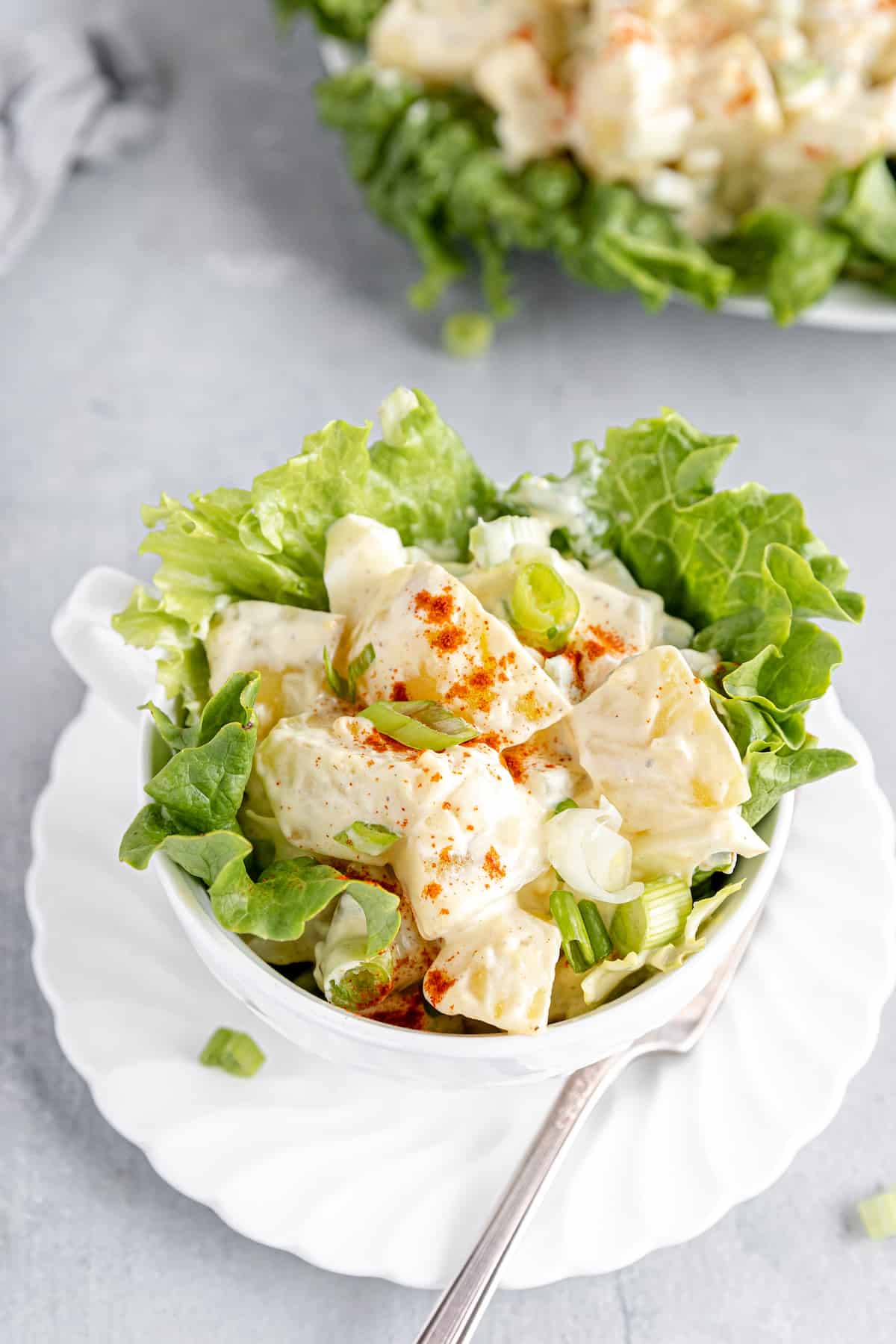 A Close-Up Shot of a Potato Salad in a Large Cup with Lettuce Leaves