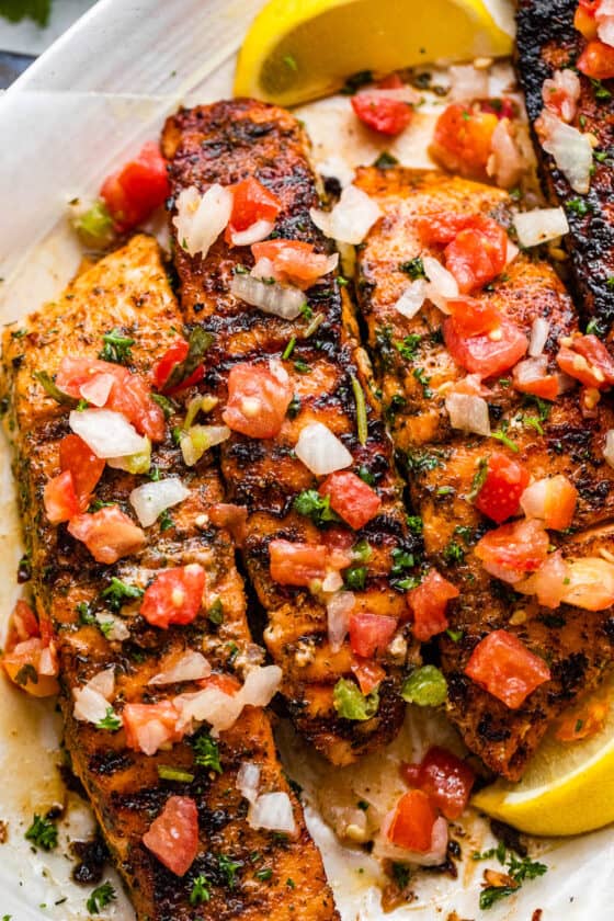 close up photo of three brown sugar grilled salmon fillets topped with pico de gallo