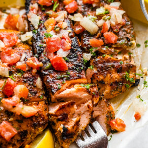three grilled salmon fillets topped with tomatoes and onions