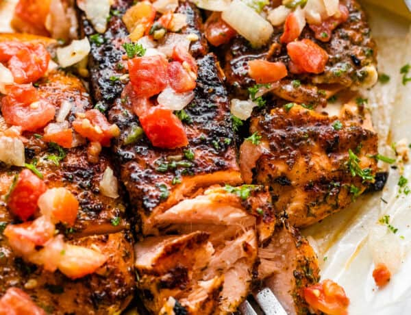 three grilled salmon fillets topped with tomatoes and onions