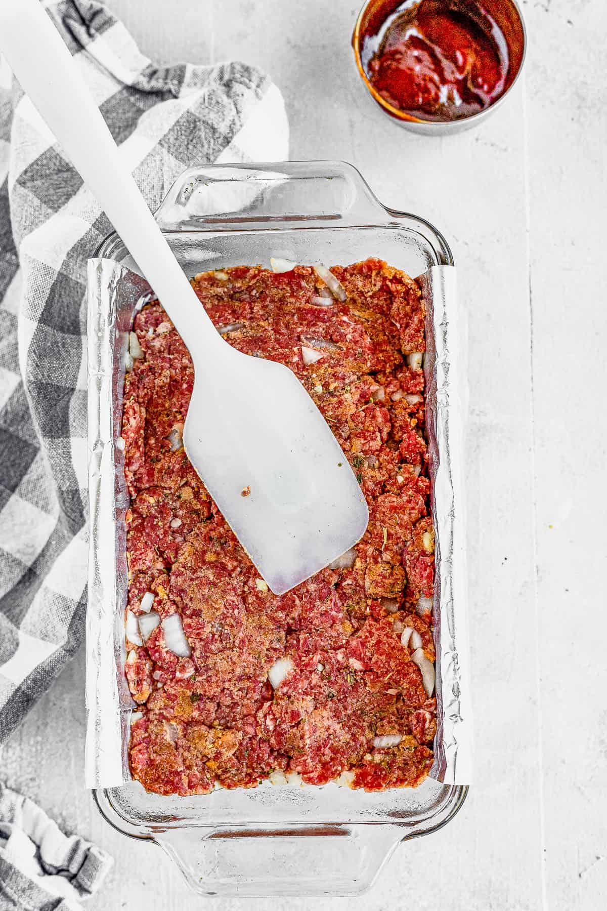 A Spatula Spreading the Meatloaf Mixture Into a Foil-Lined Pan