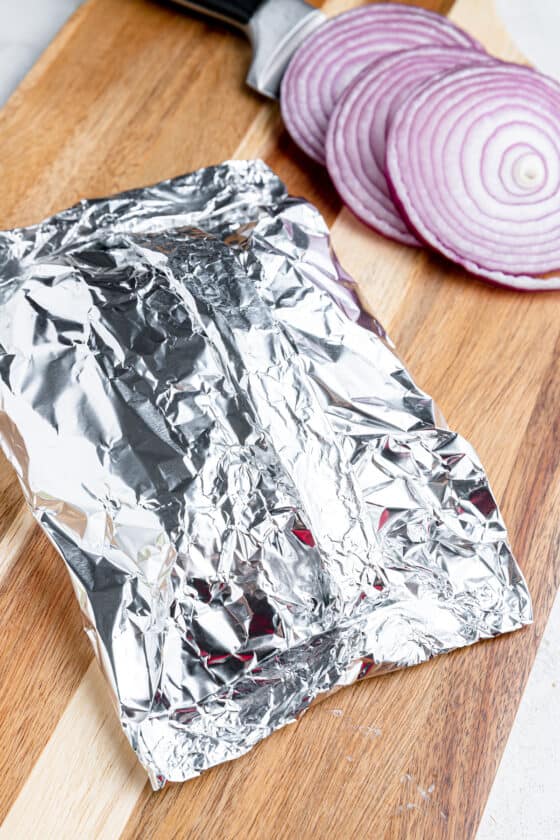 Folded foil on a cutting board and stuffed with cheeseburgers