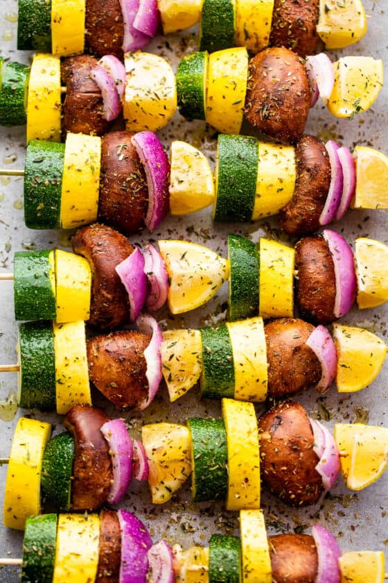 eight squash, red onions, lemons, and mushrooms threaded on wooden skewers