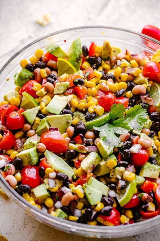 avocado, corn, tomatoes, black-eyed peas, beans and cilantro in a large glass bowl