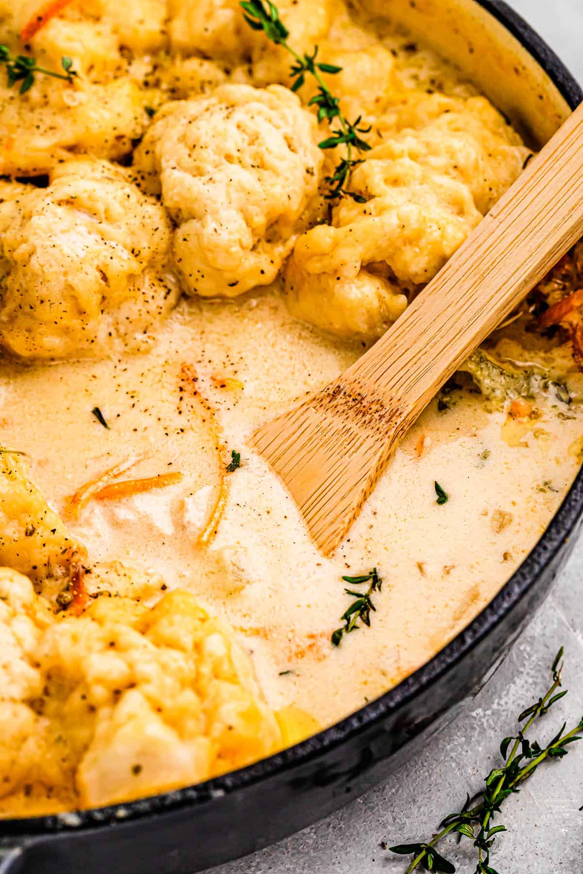 wooden spoon in a dutch oven spooning out chicken and dumplings