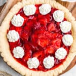 overhead shot of strawberry pie garnished with dollops of cream