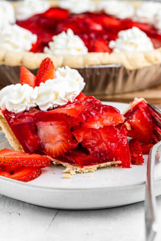 a slice of strawberry pie set on a plate with a fork