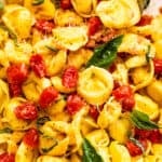 tortellini pasta tossed with cherry tomatoes and garnished with basil leaves