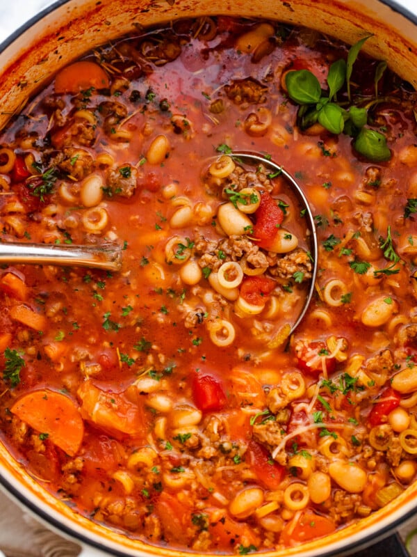 pasta fagioli soup in a white dutch oven with ladle inside the soup