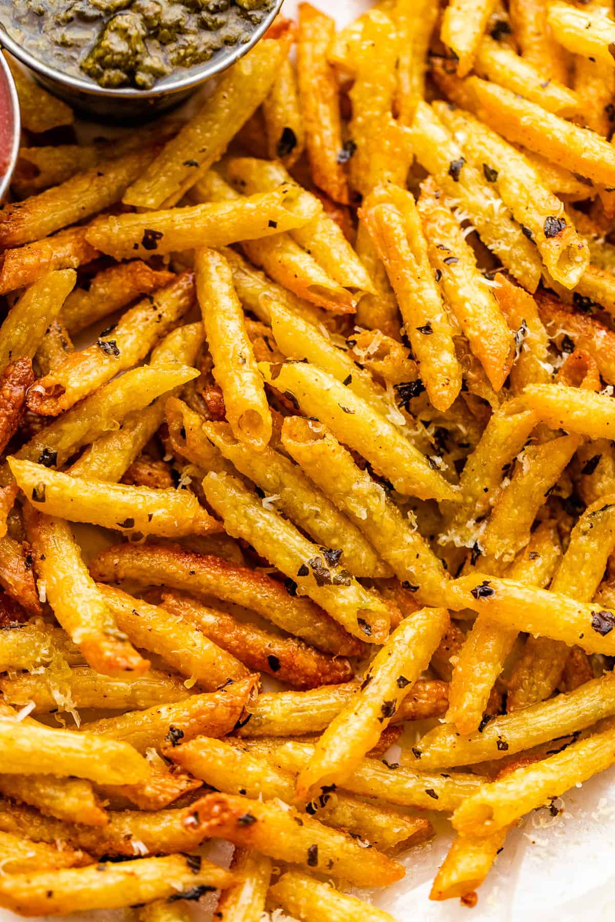 close up of baked pasta chips served with basil pesto