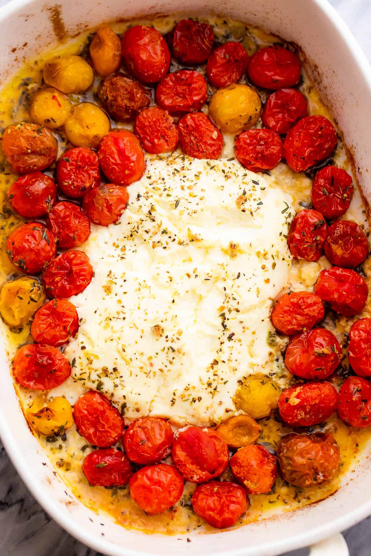a baking dish with block of cream cheese with cherry tomatoes around it