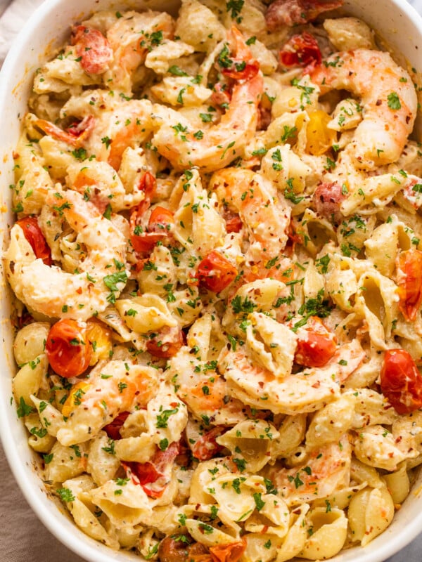 white baking dish with shrimp and pasta tossed with a cream cheese sauce and cherry tomatoes