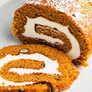 Pumpkin cake roll with one slice cut out and the filling exposed.