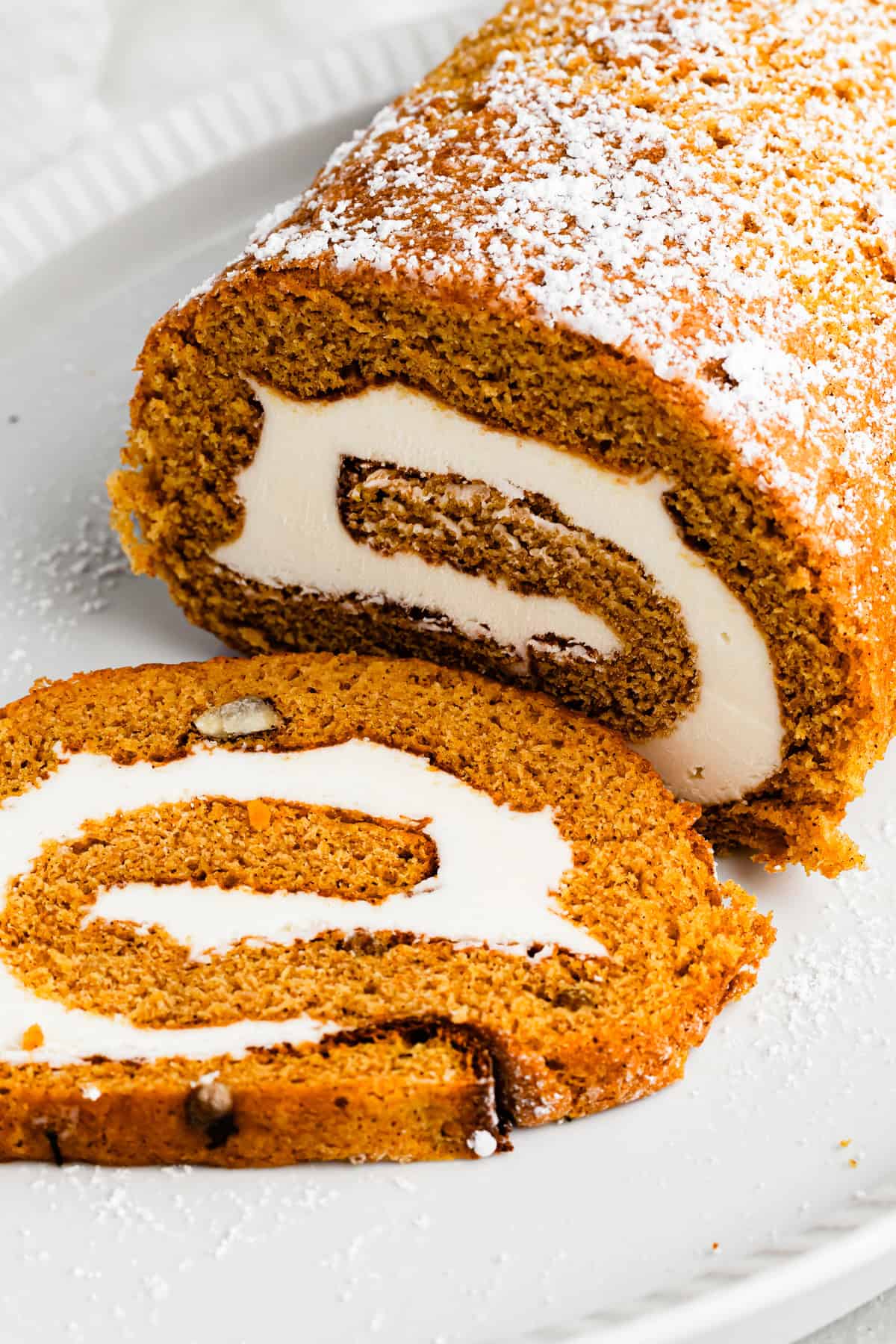 Pumpkin cake roll with one slice cut out and the filling exposed.