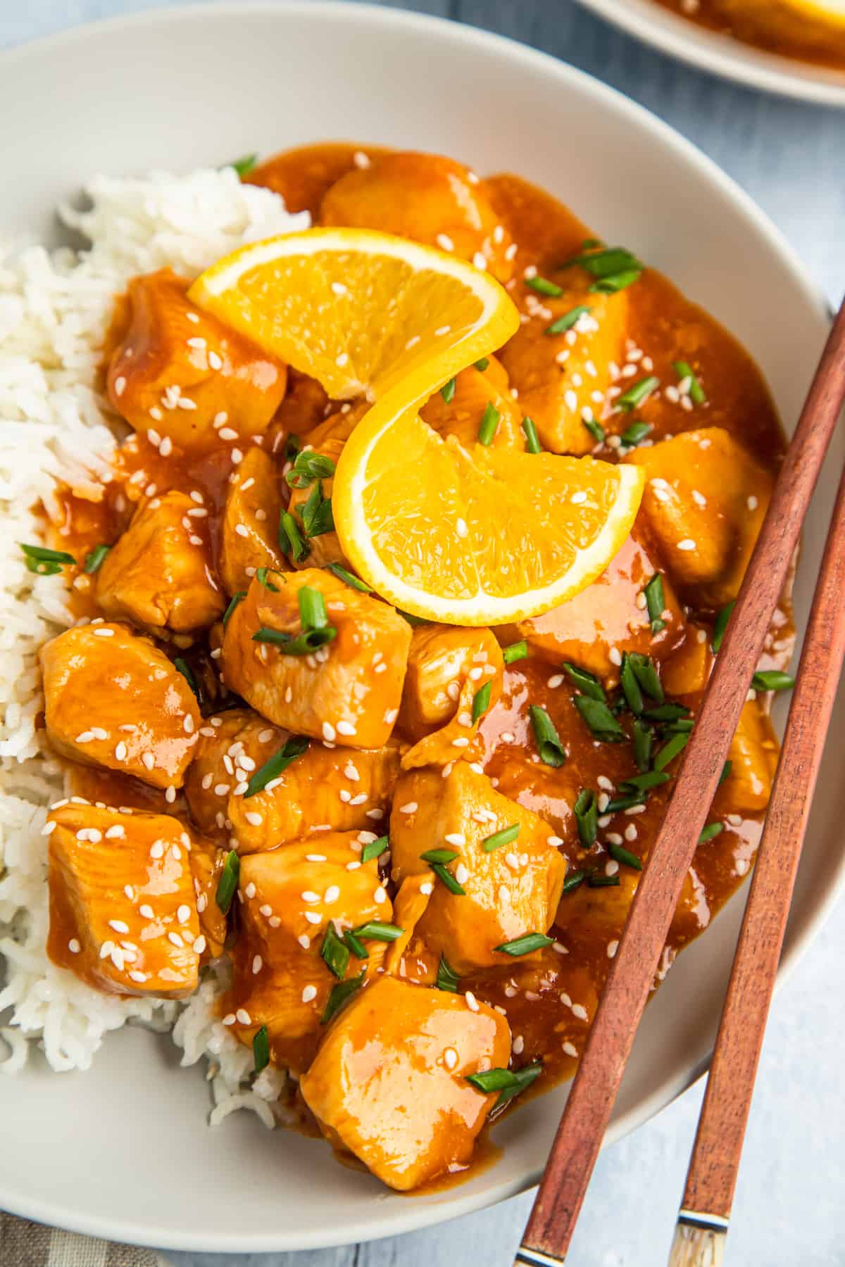 Overhead shot of orange chickn on a plate, garnished with an orange twist.