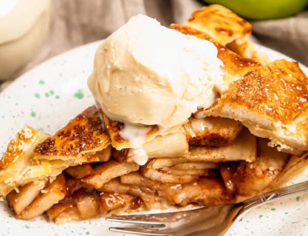a slice of apple pie topped with ice cream on a plate with a fork