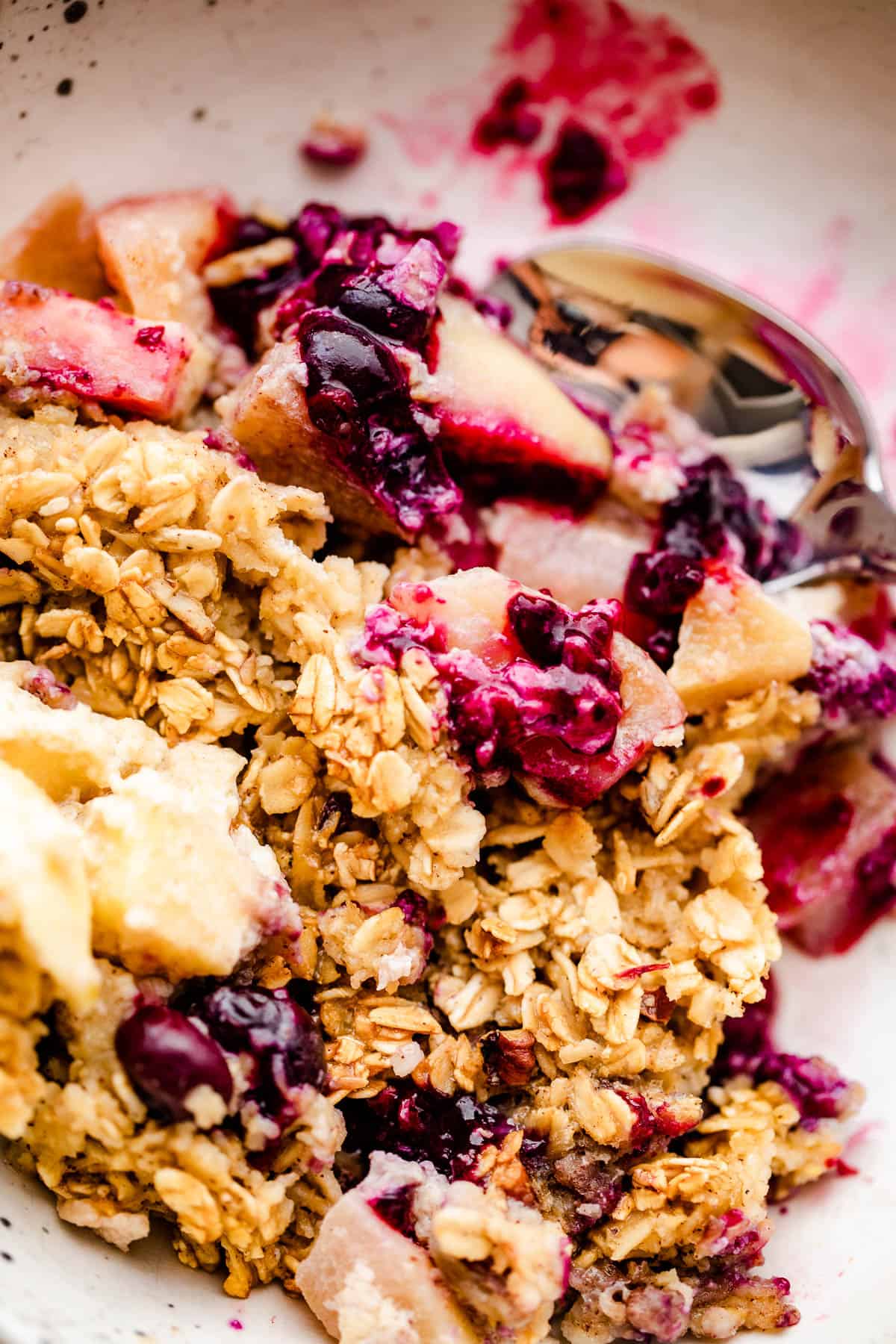 a scoop of apples and berries baked oatmeal served on a white plate.