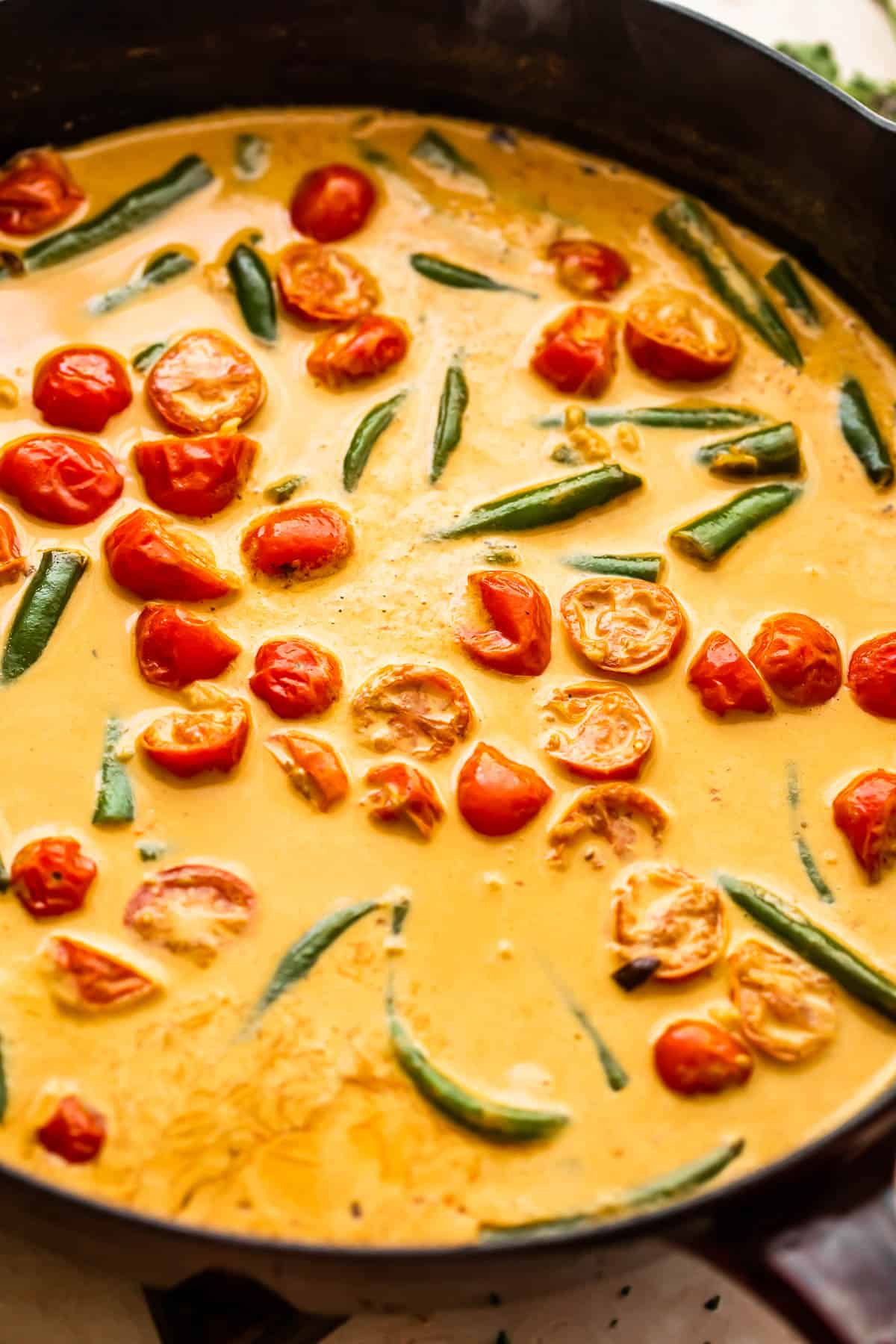 skillet with tomatoes and green beans mixed creamy sauce