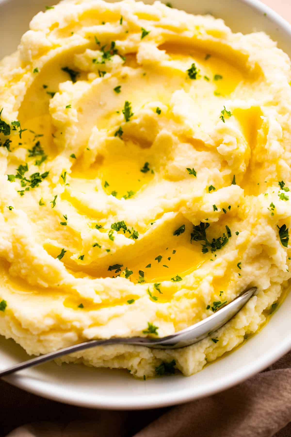 close up overhead shot of creamy mashed potatoes garnished with melted butter and parsley