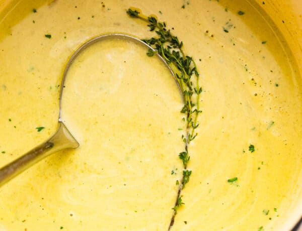 cream of asparagus soup in a pot with a ladle inside it.