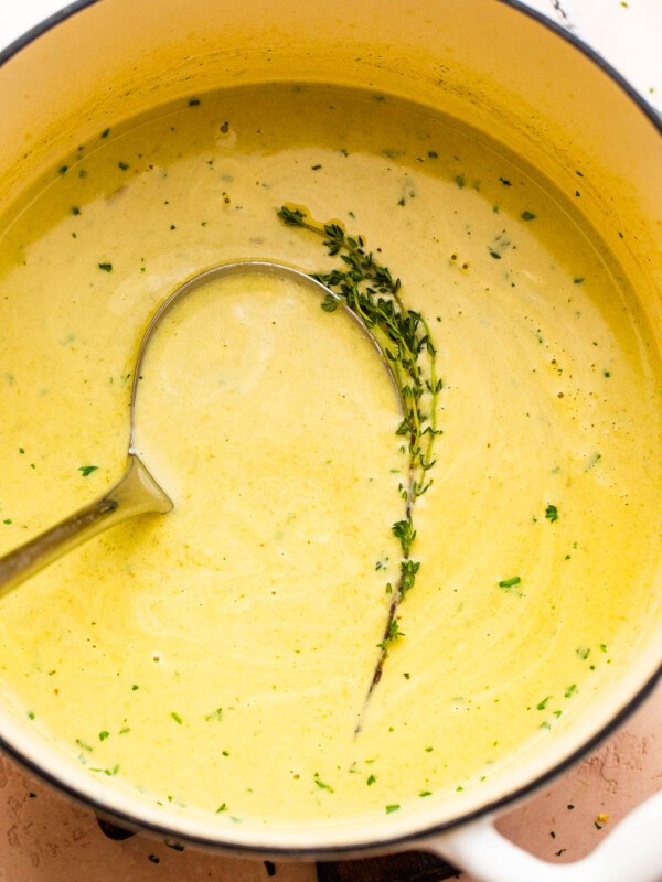 cream of asparagus soup in a pot with a ladle inside it.