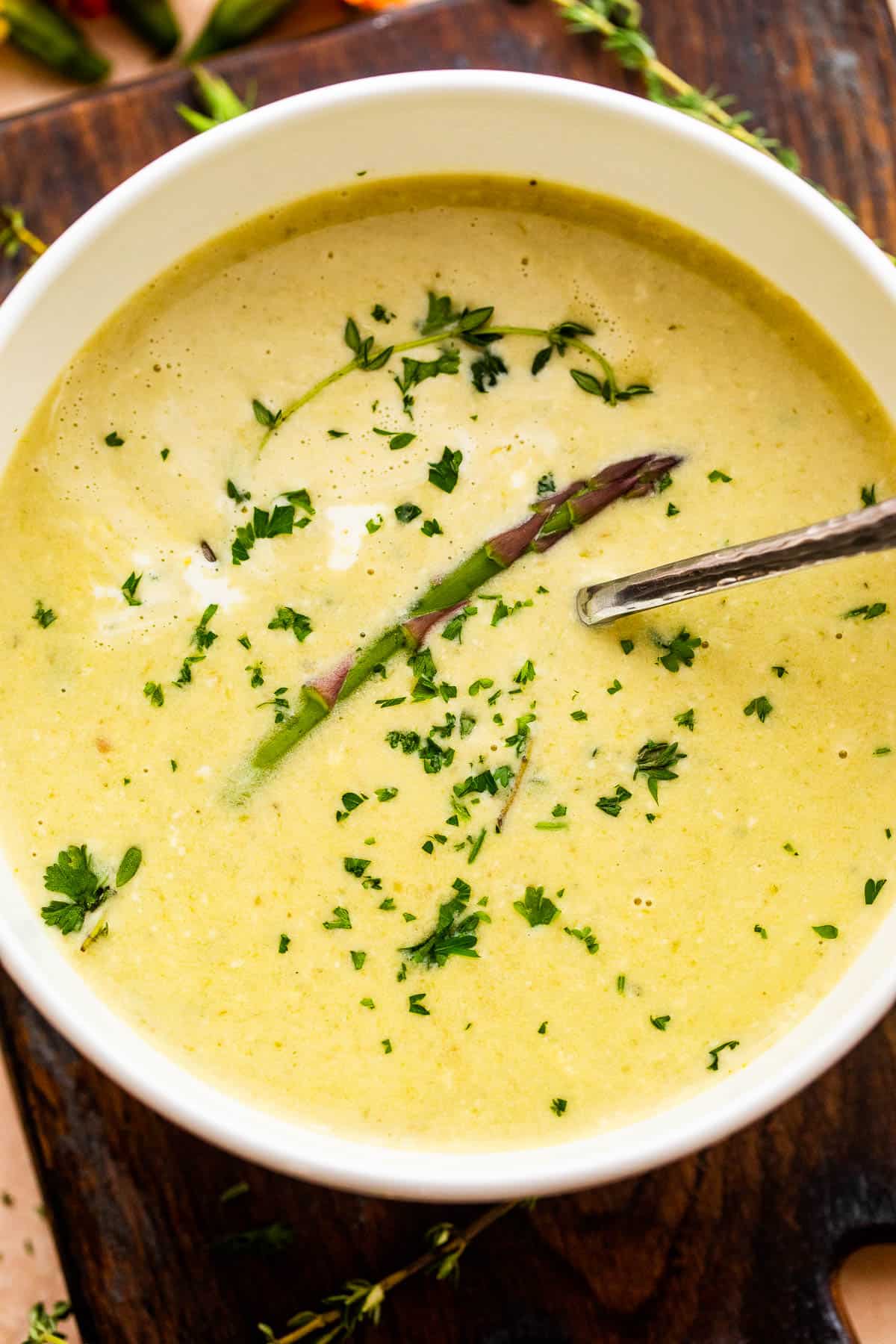 Cream of Asparagus Soup in a white bowl with a spoon inside.