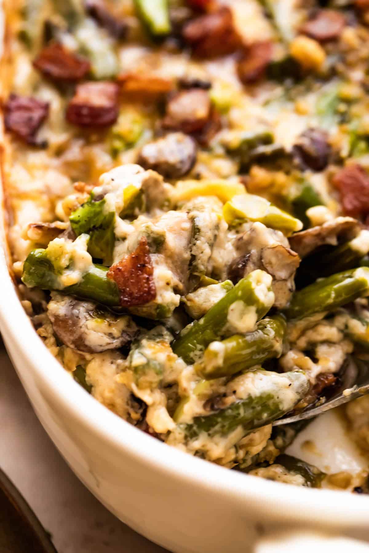 close up shot of a large spoon scraping out green bean casserole.