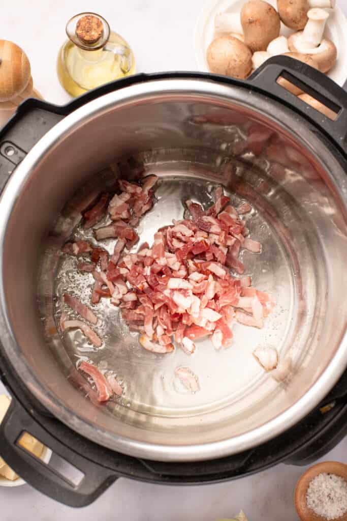 Diced bacon frying in an Instant Pot.