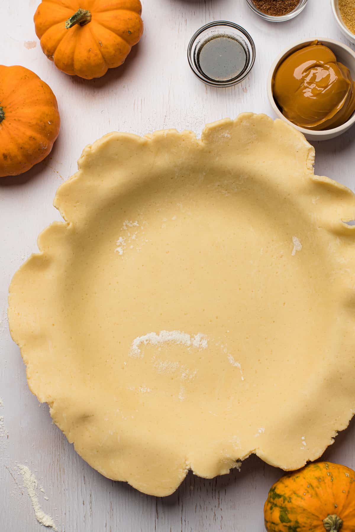 A pie plate lined with homemade pie crust that has not yet been trimmed to fit.