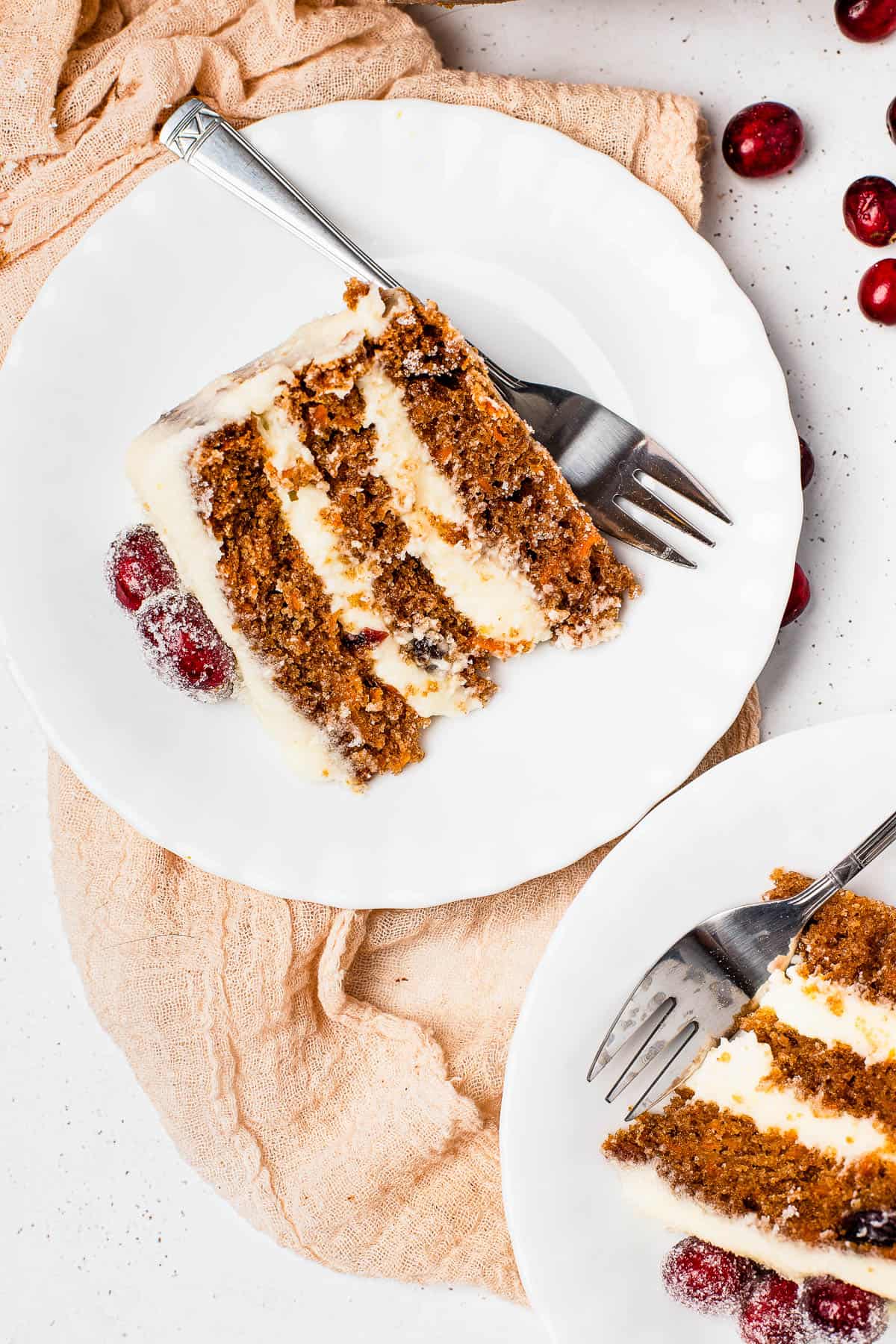 A close-up shot of a slice of cranberry carrot layer cake on a dessert plate with a fork.