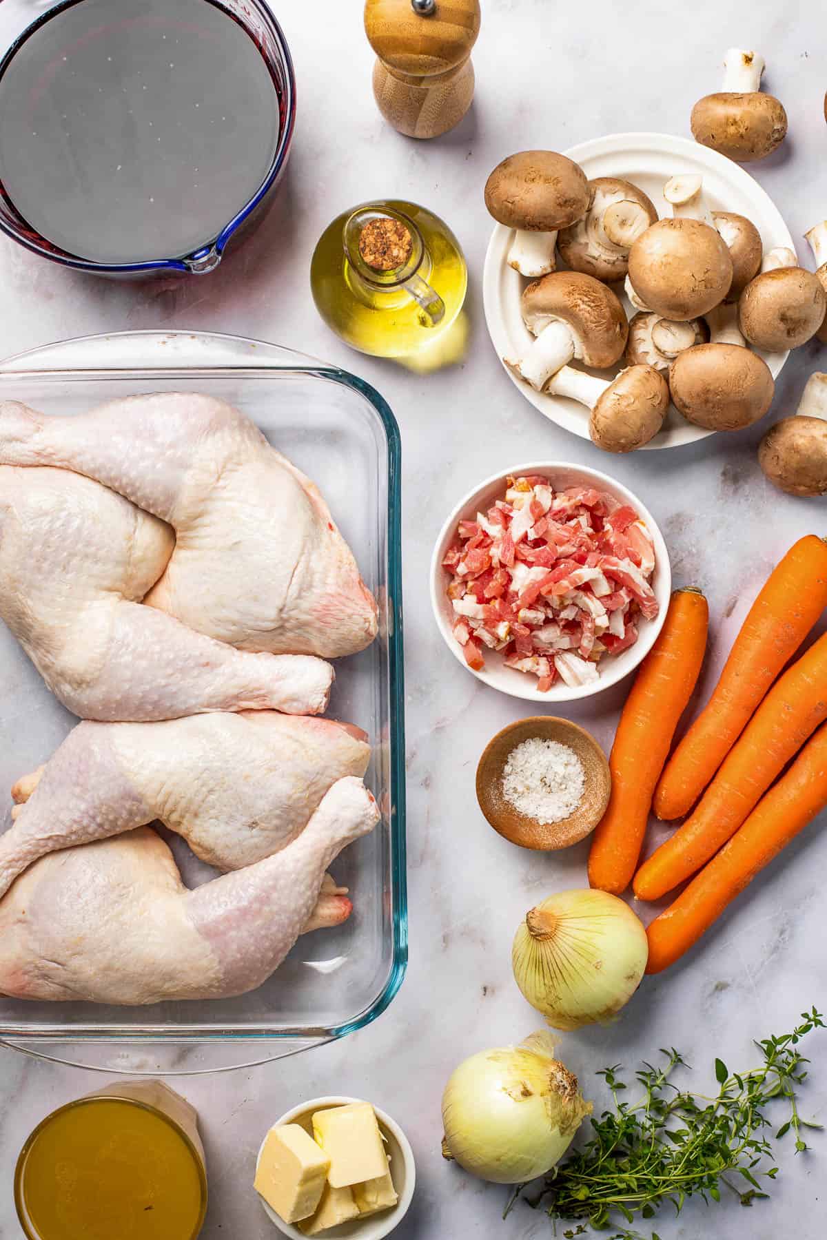 Clockwise from top: Black pepper, mushrooms, carrots, bacon, salt, onions, fresh thyme, butter, chicken leg quarters, red wine.