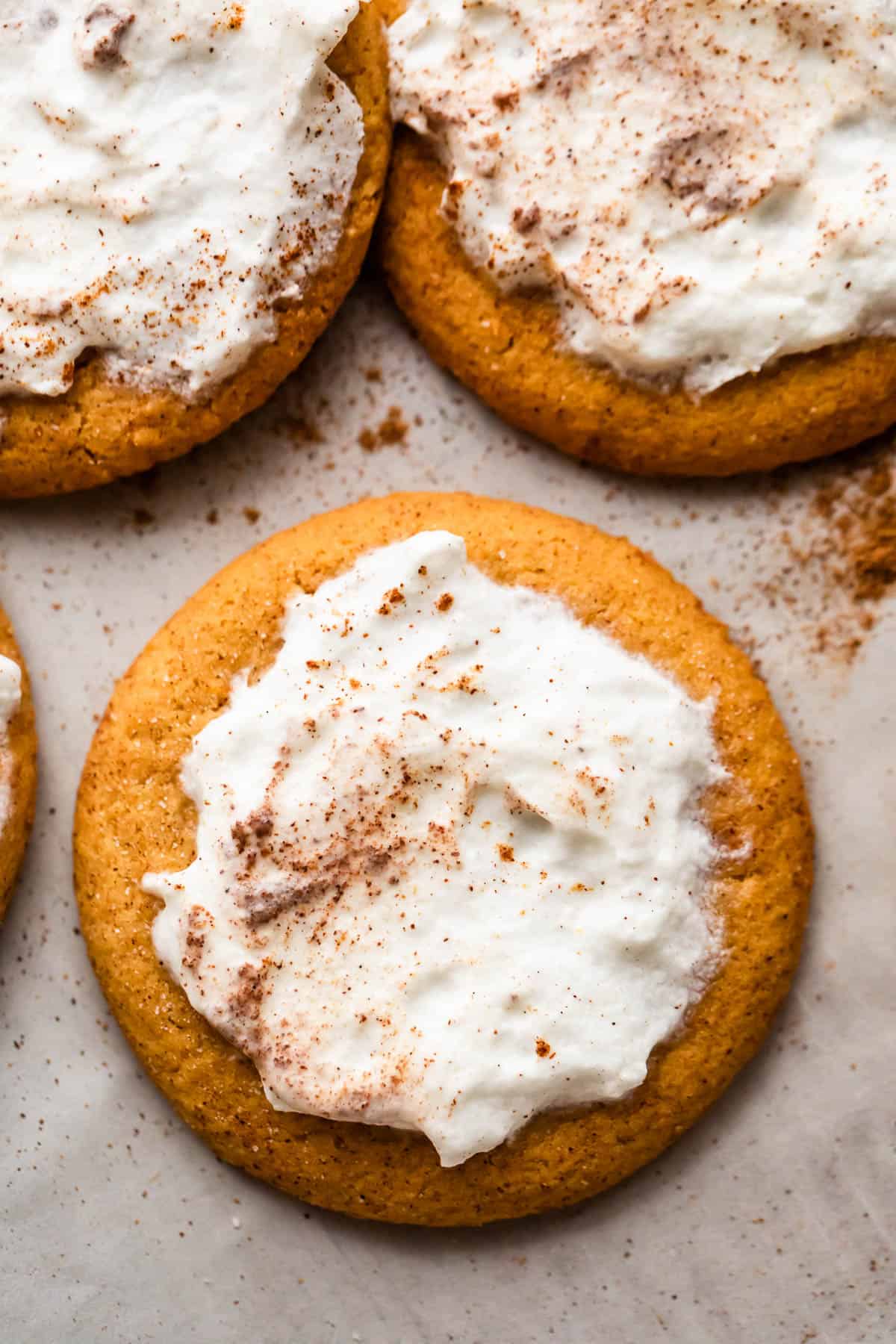 overhead shot of three pumpkin cookies topped with cream cheese frosting.