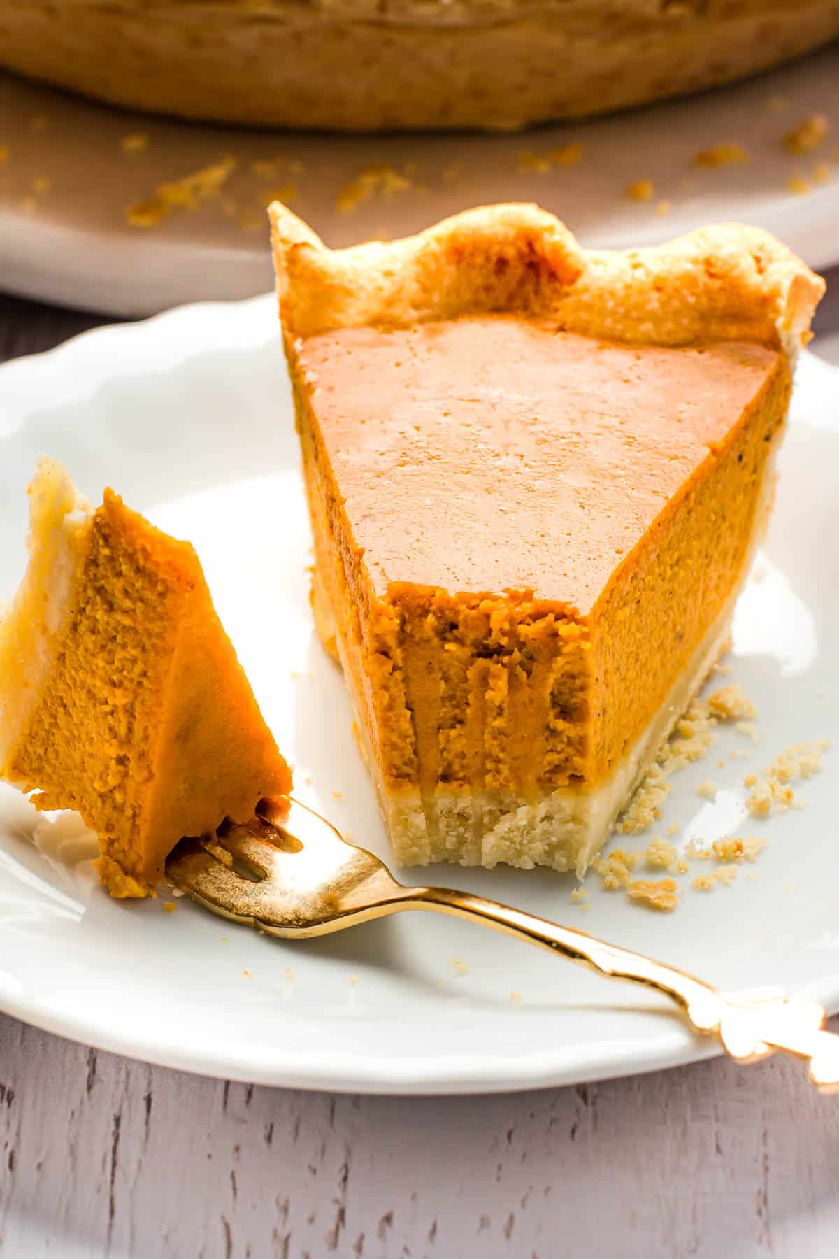 A pumpkin pie slice on a white plate with a fork.