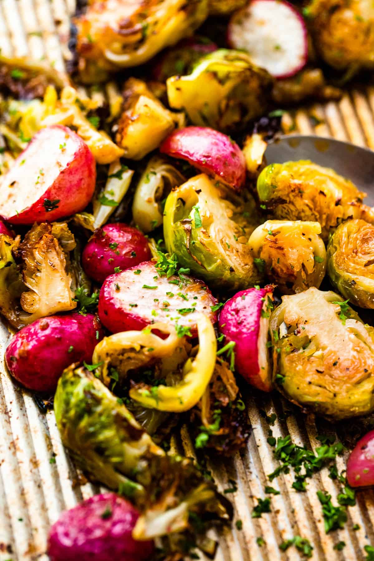 Close up shot of halved Roasted Brussels Sprouts and Radishes on a baking sheet