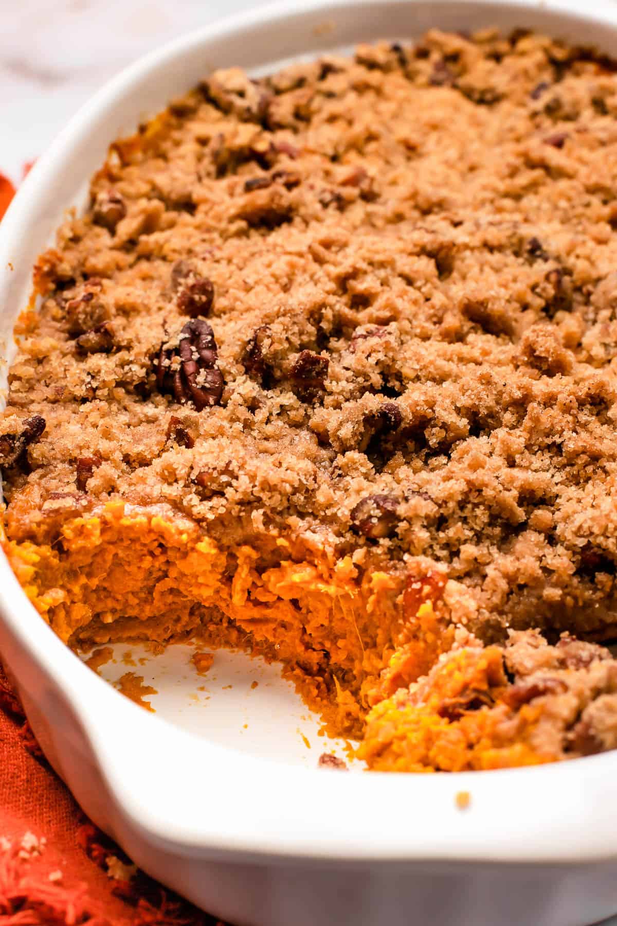 side shot of a baking dish with cut into sweet potato casserole topped with crumb topping