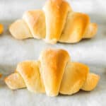 A row of crescent rolls on a parchment-lined baking sheet.