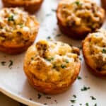 sausage breakfast cups arranged on a light plate and garnished with chopped parsley