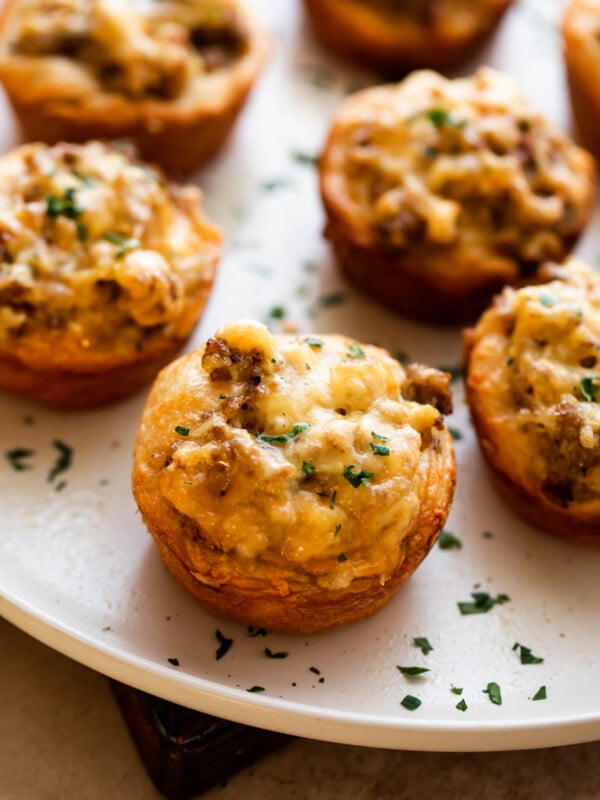 sausage breakfast cups arranged on a light plate and garnished with chopped parsley